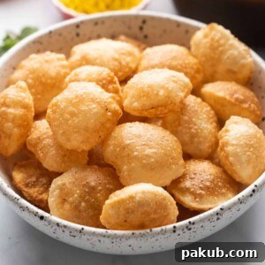 Crispy Puris served in a bowl, with the flavorful pani (spiced water) and filling elegantly arranged in the background.