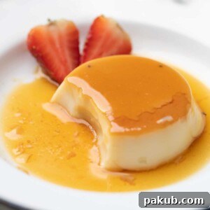 Elegant caramel custard served on a white plate, beautifully garnished with fresh strawberries on the side.