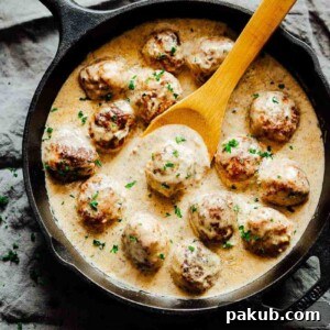 Creamy chicken meatballs in mushroom sauce, simmering perfectly in a pan.