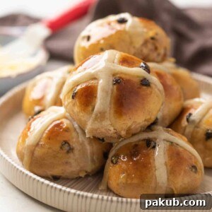 A charming pile of soft hot cross buns, neatly stacked on a black and white plate, ready to be enjoyed.