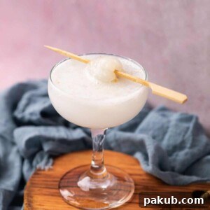 Refreshing lychee soda served in a tall glass, elegantly topped with a lychee on a toothpick.