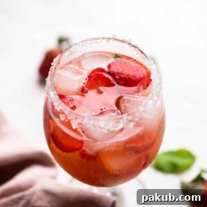 A sophisticated Strawberry Pepper Gin and Tonic, served in a short stemmed glass with a sugar-rimmed edge.