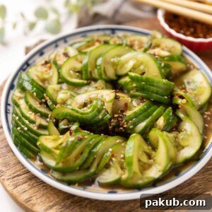 Asian cucumber salad served on a vibrant white and blue plate, featuring perfectly sliced Persian cucumbers tossed in a rich, flavorful dressing.