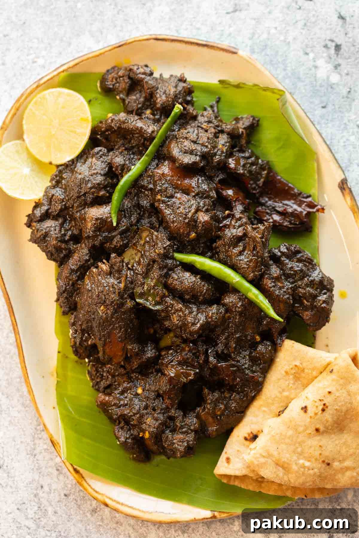 Assamese black sesame chicken curry served on a platter with freshly made rotis and a slice of lime, ready to be enjoyed.