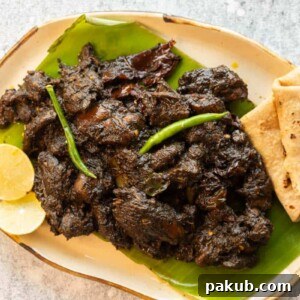 Black sesame chicken served on a platter with rotis and lime, showcasing the rich color of the curry.