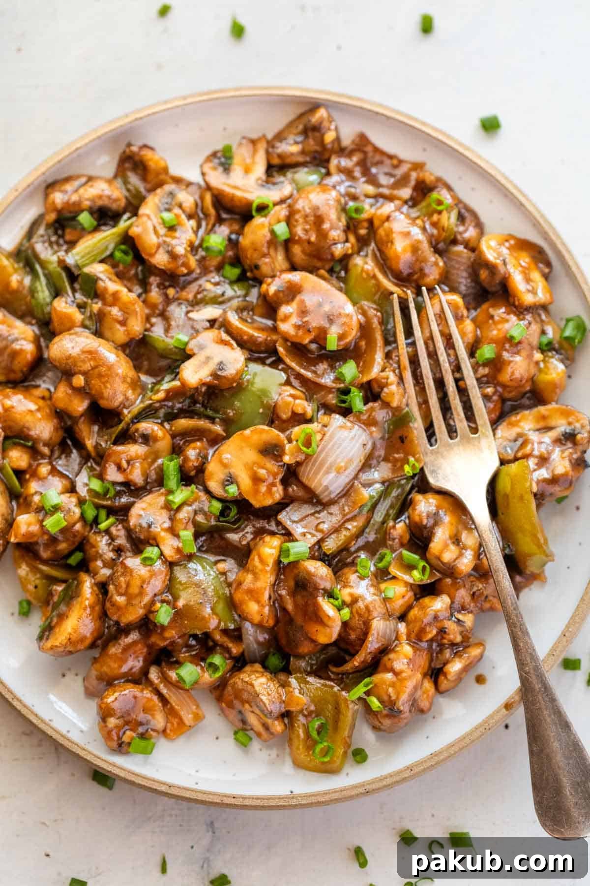 Delicious Air Fryer Mushroom Chilli served on a white plate with a fork on the side, ready to eat.