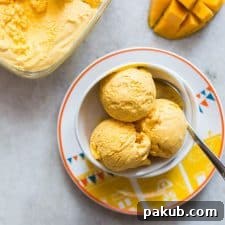 Three scoops of Homemade Mango Cheesecake Ice Cream served in a white bowl, looking deliciously creamy.