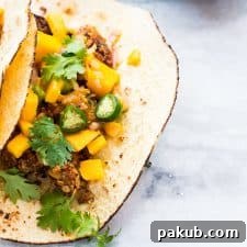 The healthy oats crusted fish tacos filled with fresh mango salsa, served on a plate.