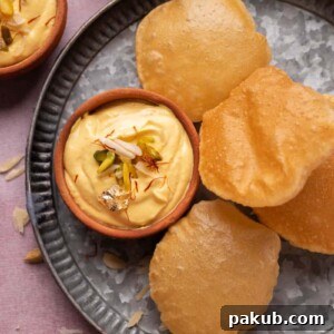 Mango Shrikhand served on a plate with pooris, a traditional Indian bread.