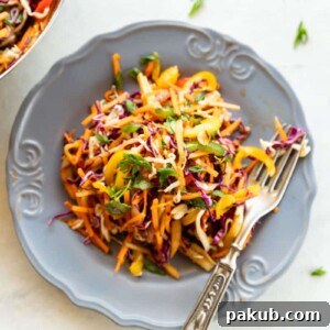 Asian Slaw in a grey bowl with fork on white background