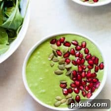 A beautifully crafted Vegan Spinach Ginger Smoothie Bowl, generously topped with fresh pomegranate seeds and pumpkin seeds, offering a nutritious and colorful start to the day.