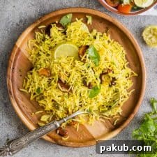 A serving of flavorful Easy Lemon Rice (Yellow Rice) presented on a wooden plate with a spoon, showcasing its vibrant color and aromatic appeal.