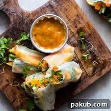 Vibrant Mango Bell Pepper Rice Paper Rolls, accompanied by a delectable Mango Cilantro Dipping Sauce, artfully arranged on a wooden board, showcasing a fresh and colorful appetizer.