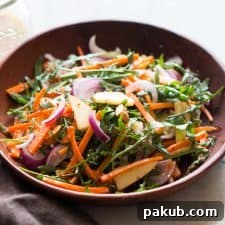 A vibrant Apple Arugula Almond Salad with Orange Dressing, presented beautifully in a bowl, highlighting the fresh greens, crisp apple slices, and slivered almonds.
