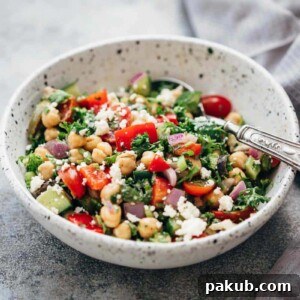 An inviting Easy Mediterranean Chickpea Salad served in a rustic ceramic bowl with a spoon, showcasing colorful vegetables and robust flavors.