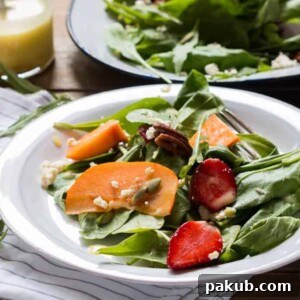 A beautiful Greens, Persimmon Ricotta Salad with Orange Dressing, garnished with fresh ricotta and presented on a clean white plate, offering a delightful blend of sweet and savory.