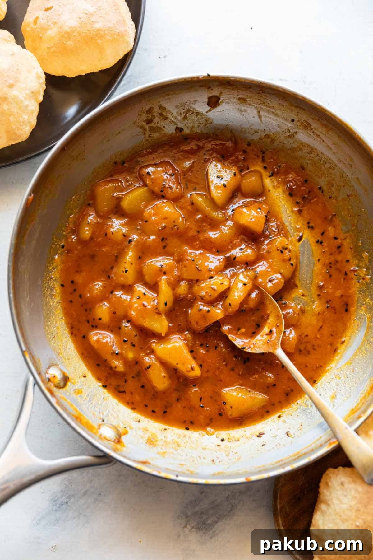 Tangy Green Mango Relish 2 Raw mango chutney in a pan with a spoon and served with pooris