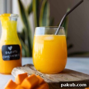 A glass jar filled with vibrant homemade mango juice, garnished with a straw, ready to refresh on a hot day.