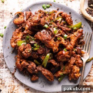 Crispy Salt and Pepper Chicken served elegantly on a grey plate with a fork, inviting you to taste.