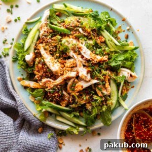 Spicy chicken cucumber salad served generously with a side of homemade chili oil, highlighting its fresh ingredients and vibrant dressing.