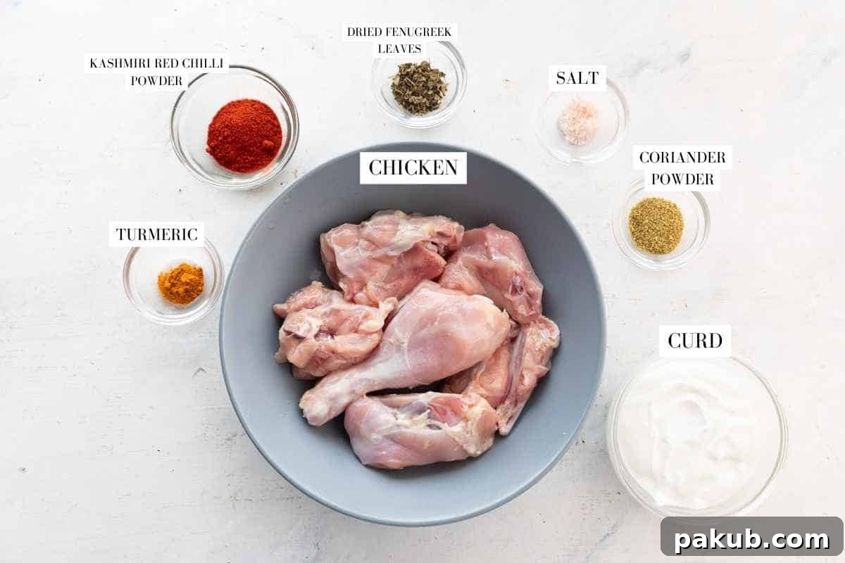 Selection of spices including turmeric, red chili, coriander, and fenugreek leaves, along with whipped curds and chicken pieces, all laid out for the marinade of the pressure cooker chicken curry.