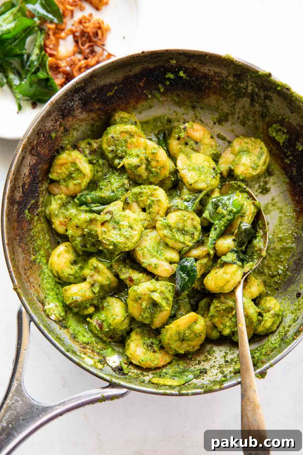 Close-up shot of perfectly cooked curry leaf prawns in a pan with a serving spoon