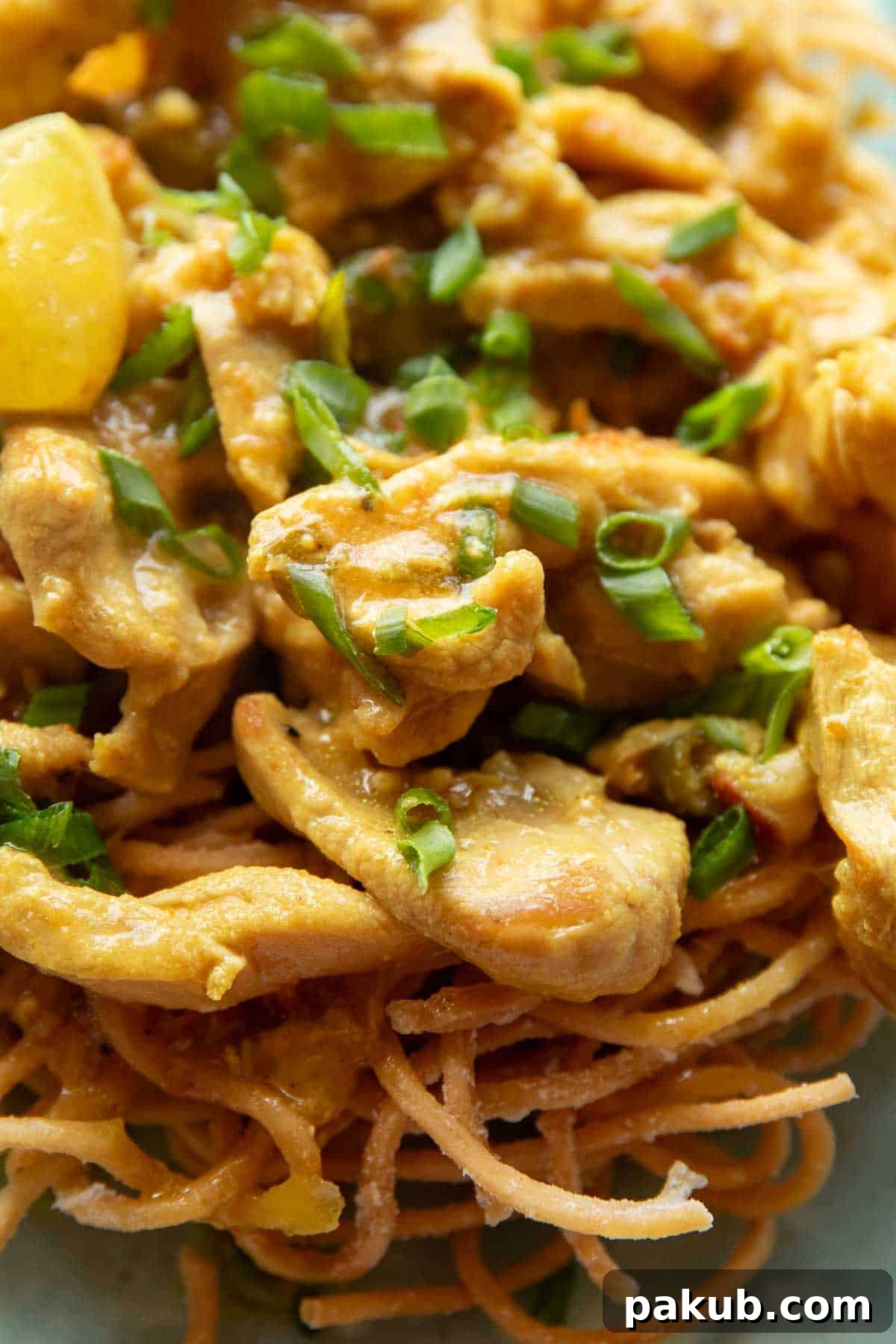 Close-up shot of perfectly cooked Lemon Chicken pieces nestled among crispy fried noodles, highlighting the juicy texture of the chicken and the rich, zesty sauce ready to be served.