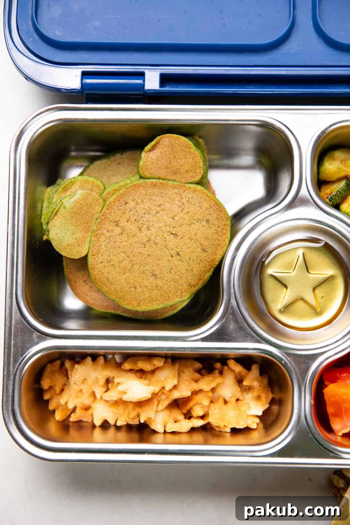 Wholesome Green Banana Flapjacks 3 Mickey Mouse shaped green spinach banana pancakes neatly arranged in a tiffin box, perfect for a fun and healthy kid's lunch or snack.