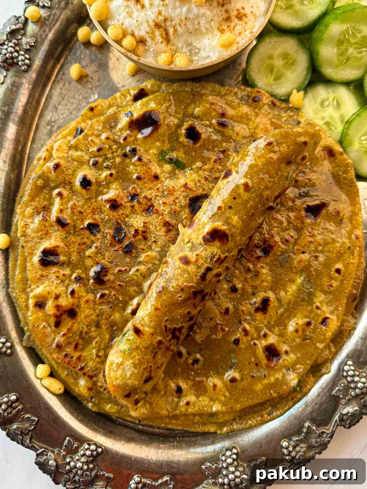 Spiced Lentil and Chutney Paratha 2 Closeup of golden brown dal parathas piled on top of each other, with one rolled up to show its fluffy interior.