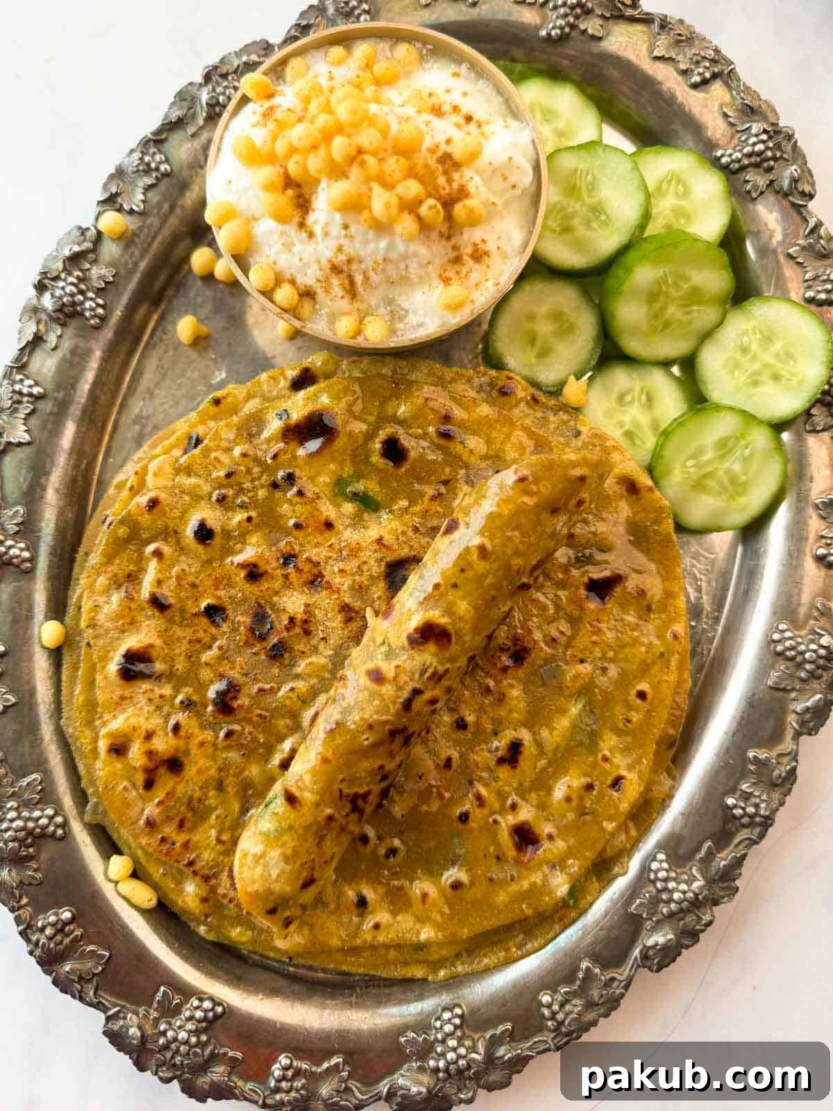 Spiced Lentil and Chutney Paratha 4 Dal paratha served attractively on a platter with a side of fresh yogurt and crisp cucumber slices, ready to be enjoyed.