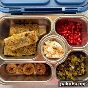 Dal paratha served in a kids tiffin box with fruits, nuts, curd and veggies