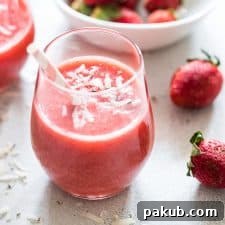 A refreshing Strawberry Banana Coconut Smoothie, garnished with grated coconut and served with a straw for tropical vibes