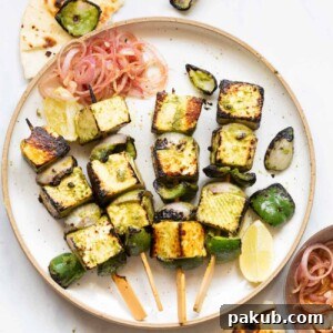 A vibrant shot of Hariyali Paneer Tikka skewers elegantly arranged on a white plate, garnished with fresh herbs.