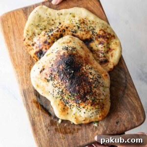 A delicious Thecha Naan, generously stuffed with chili and cheese, presented on a rustic wooden board.