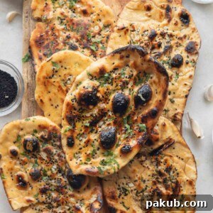 A stack of golden-brown butter garlic naan, layered beautifully on a wooden board, showcasing its soft and fluffy texture.