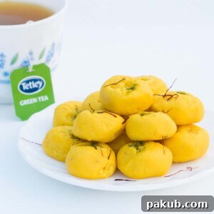 Easy Kesar Pedas, delicately arranged on a white plate, served with a side of refreshing Tetley green tea.