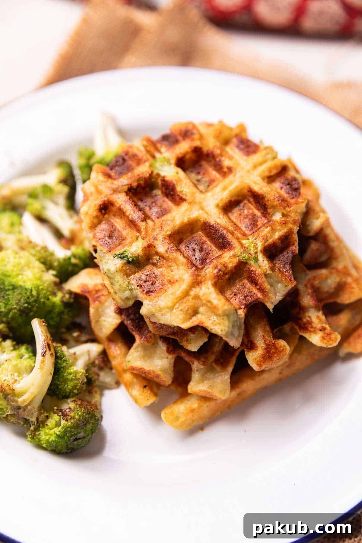 Broccoli Cheddar Waffles 3 Two golden-brown Broccoli Cheese Waffles served elegantly on a white plate, garnished with fresh herbs, emphasizing their savory appeal and delicious texture