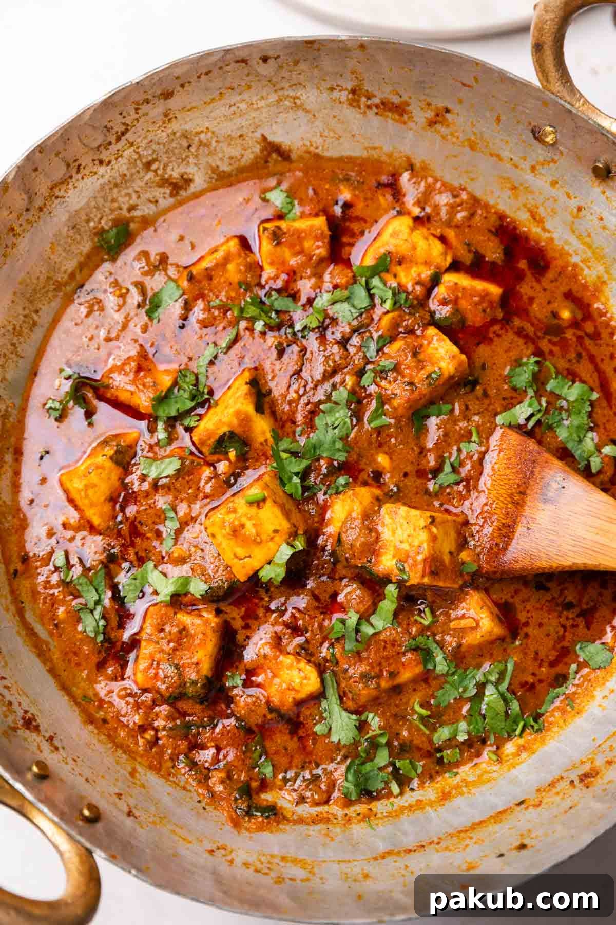 Dhaba style paneer masala in a kadhai with a wooden ladle, showcasing its rich texture and color