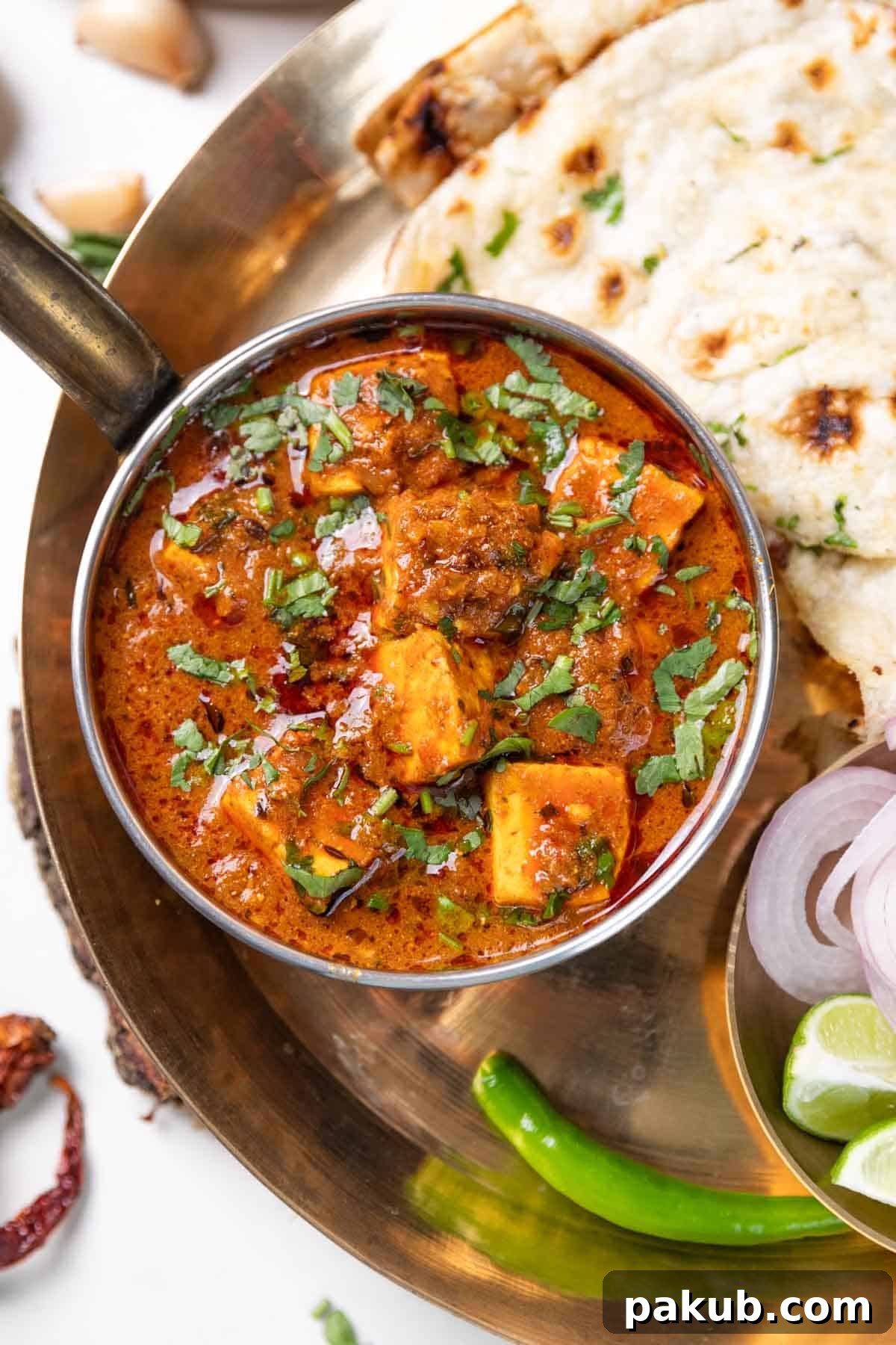 Dhaba style paneer masala served with fresh naan, green chili slices, onion rings, and a lemon wedge