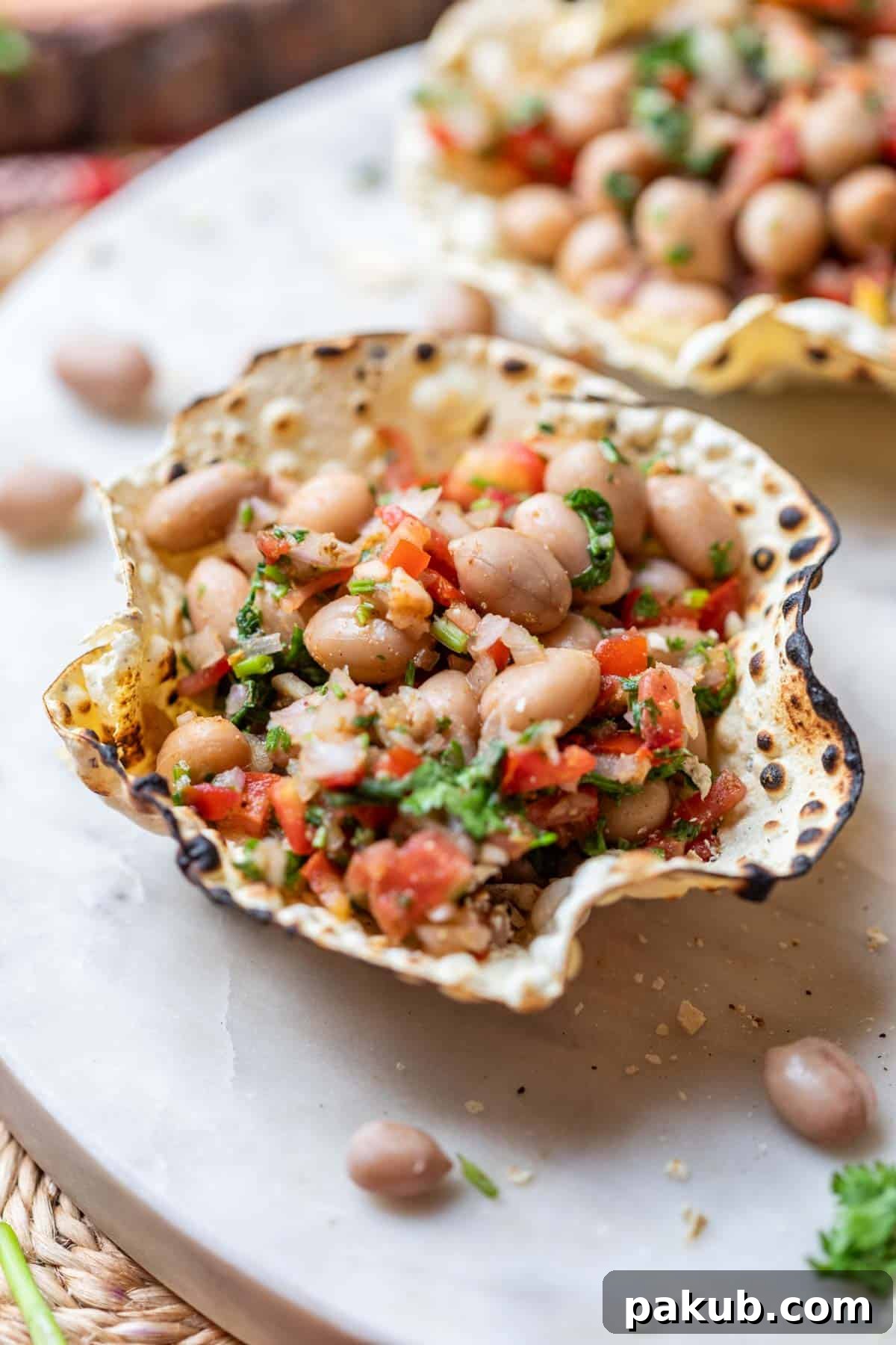 Crispy Papad Chaat Bowl 3 Close-up view of perfectly formed edible papad bowls filled with a colorful and spicy peanut chaat, presented on a minimalist white platter.