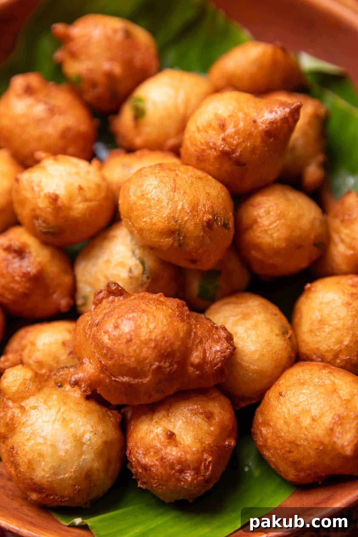 Mangalore Bajji 3 A plate of golden Goli Bajji fritters garnished with curry leaves, ready to be enjoyed as a snack.