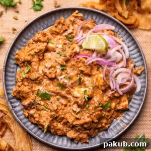 An appetizing image of chicken bharta served with sliced onion and lemon wedges, ready to eat.