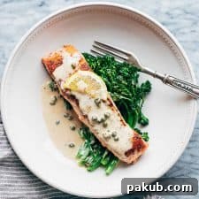 Creamy Salmon Piccata with a luscious Lemon Sauce, elegantly served with fresh greens on a white plate