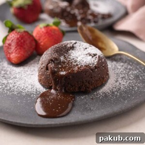 A decadent picture of rich chocolate oozing out of a molten mocha lava cake, beautifully served with fresh strawberries on the side
