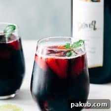 A refreshing Summer Berry Red Wine Spritzer, garnished with fresh mint and an assortment of berries, served in elegant glasses