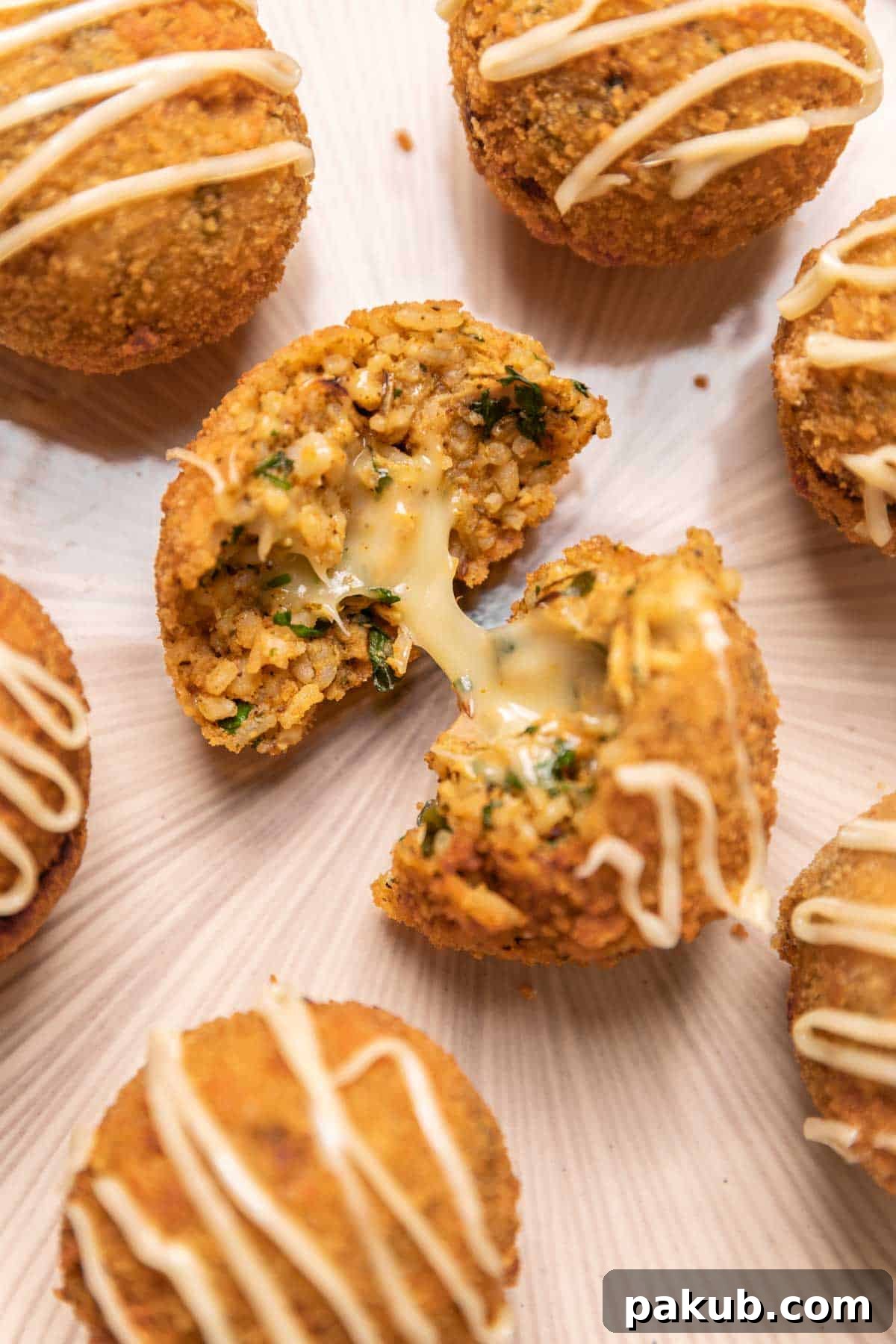 A chicken curry rice ball sliced in half, revealing its crispy exterior, flavorful curry and rice interior, and a melted, gooey mozzarella cheese center.