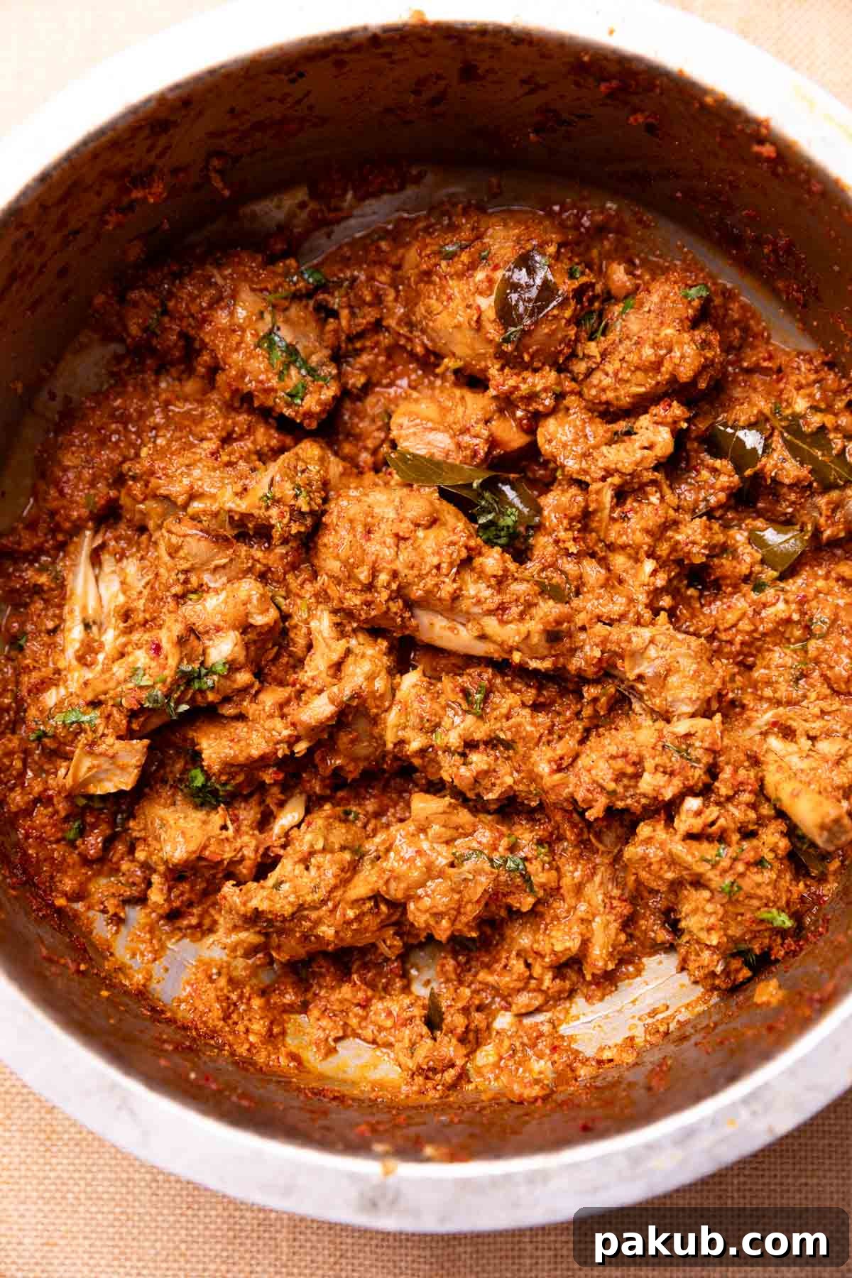 Spicy Mangalorean Chicken Sukka 3 Mangalorean Chicken Sukka simmering in a traditional Indian kadai, showcasing its rich, semi-dry texture and vibrant colors, ready to be stirred.