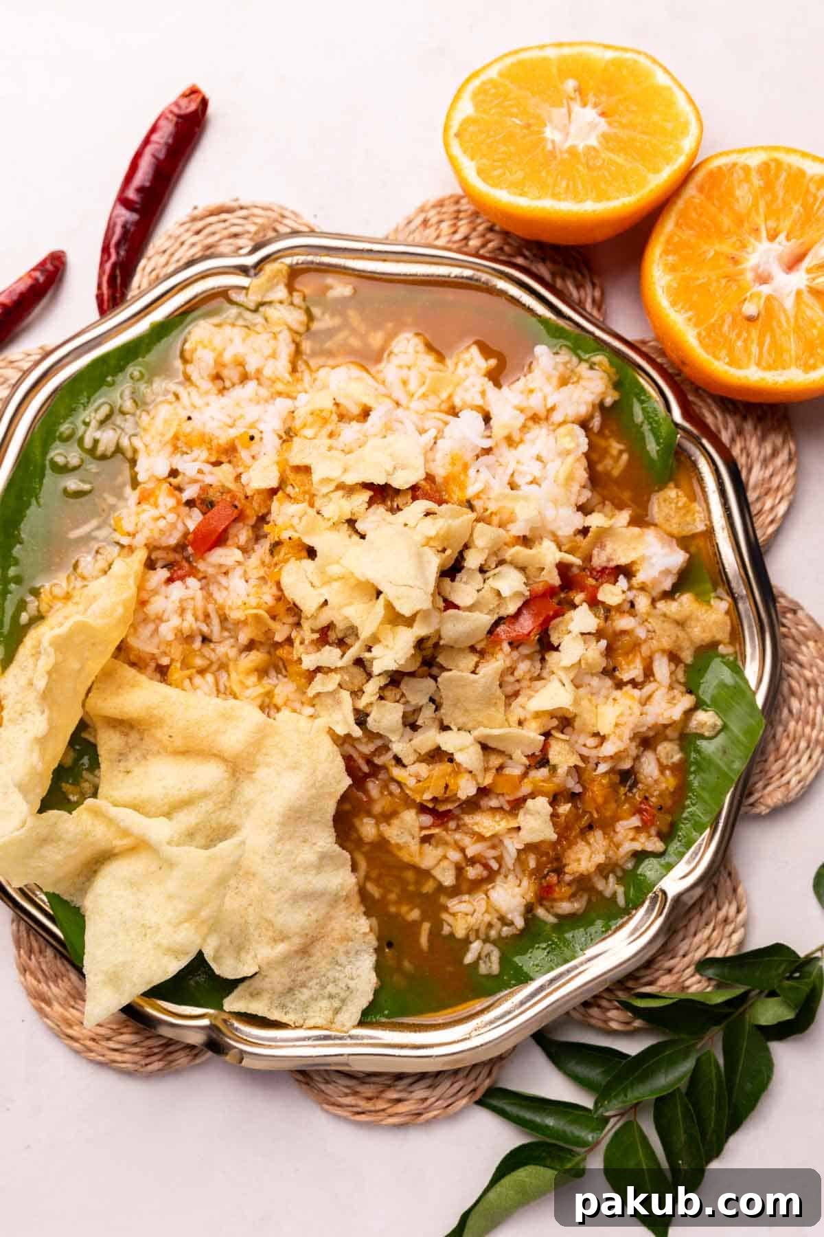 A beautifully presented South Indian meal with a bowl of orange rasam, steamed rice, and other accompaniments, showcasing its versatility.