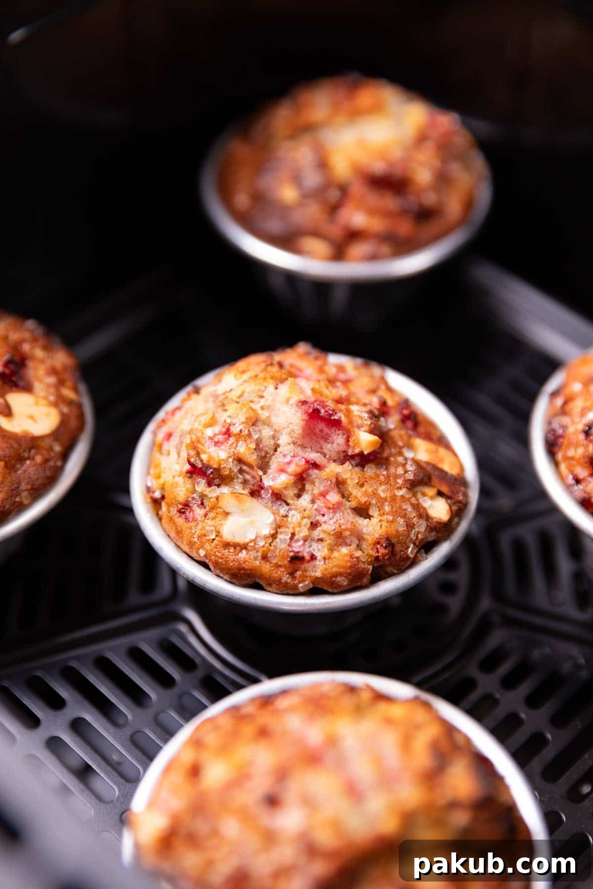 Strawberry Burst Air Fryer Muffins 2 Closeup image of freshly baked strawberry muffins with a golden, crinkly top in an air fryer basket