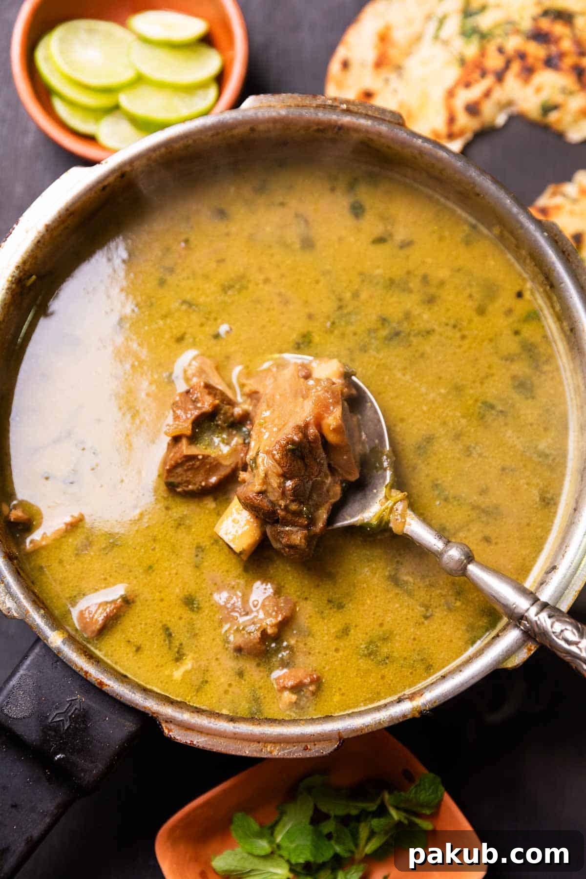 Savory Mutton Marag Broth 3 A deep bowl of Hyderabadi Mutton Marag, perfectly garnished with fresh coriander, with a spoon revealing generously sized pieces of tender, aromatic lamb